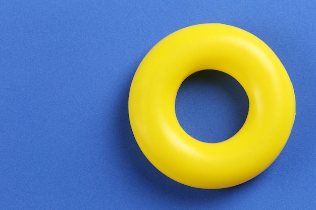 Gele rubberen ring geplaatst op een blauw papier achtergrond.