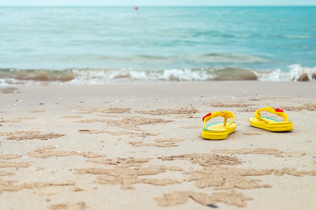 Gele sandalen op het strand.
