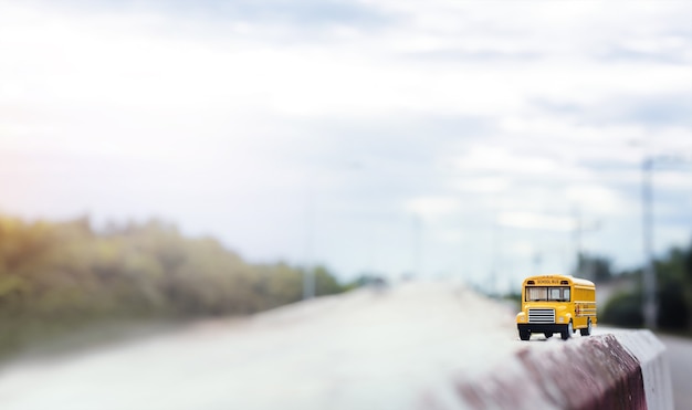 Gele schoolbus speelgoed model op landweg. Terug naar school, onderwijs en transpotation concept achtergrond.