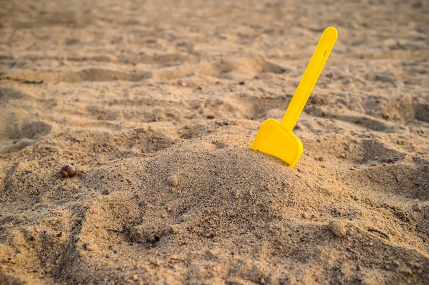 Gele schop voor kinderen vast in een hoop zand op het strand