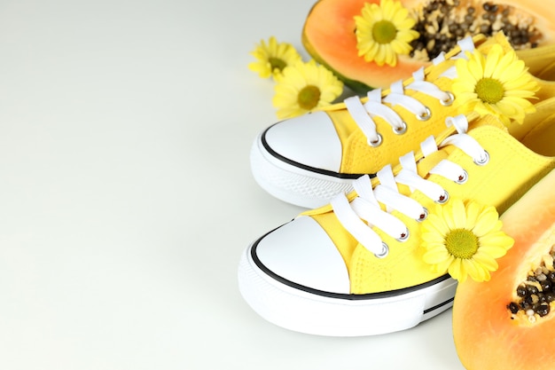 Gele sneakers met bloemen en papaya op lichtgrijze achtergrond