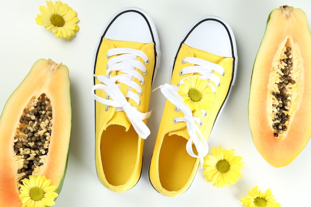 Gele sneakers met bloemen en papaya op witte achtergrond