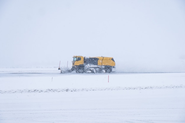 Gele sneeuwploegen ploegen besneeuwde weg in blizzard