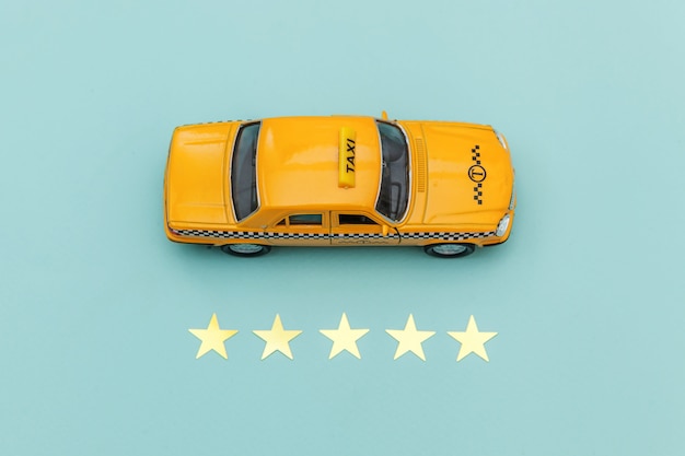 Gele speelgoedauto Taxi Cab en 5 sterren rating geïsoleerd op blauwe achtergrond.