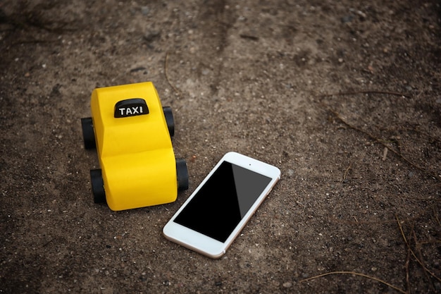 Gele speelgoedtaxi met telefoon op de grond