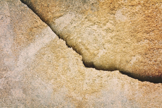 Gele steenoppervlakte met een barst achtergrondtextuur Toned