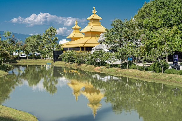 Gele tempel die in het meer in noordelijk Thailand wordt weerspiegeld