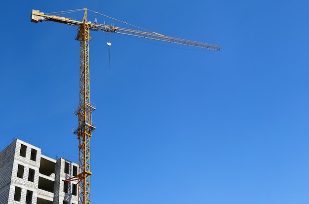 Gele torenkraan terwijl het bouwen van een huis tegen een blauwe hemel