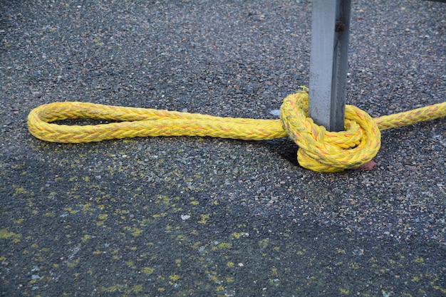 Foto gele touw vastgebonden aan een metalen paal op straat