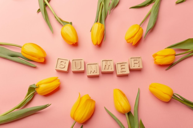 Gele tulpen en Pasen decor op een roze achtergrond Houten letters Zomer gecentreerd Bovenaanzicht