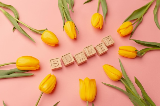 Gele tulpen en Pasen decor op een roze achtergrond Houten letters Zomer gecentreerd Bovenaanzicht