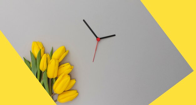 Gele tulpen en wijzers op een gele en grijze achtergrond