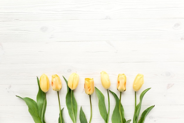 Gele tulpen geïsoleerd op een witte houten achtergrond lag plat bovenaanzicht