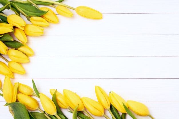 Gele tulpen op witte houten achtergrond. Bovenaanzicht, kopieer ruimte