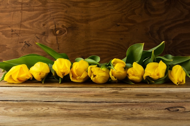 Gele tulpenrij op houten achtergrond, exemplaarruimte