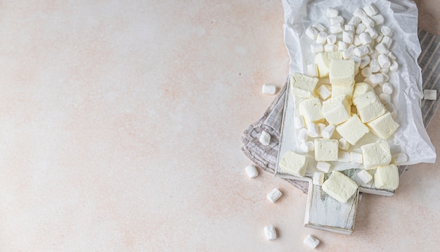 Gele vierkante vorm marshmallow en witte vanille marshmallow op houten snijplank