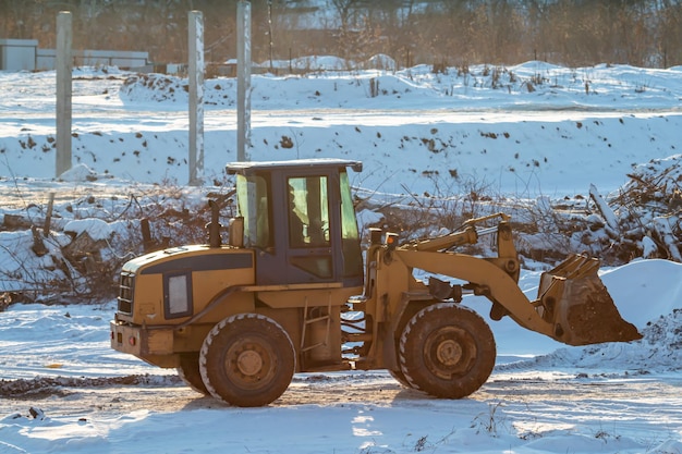 Gele voorlader trekker op wielen op een bouwplaats in de winter