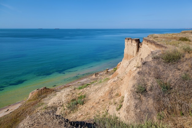 Gele zanderige rotsen en stenen van verschillende vormen aan de kust van de Zwarte Zee. Blauwe lucht en turkoois water.