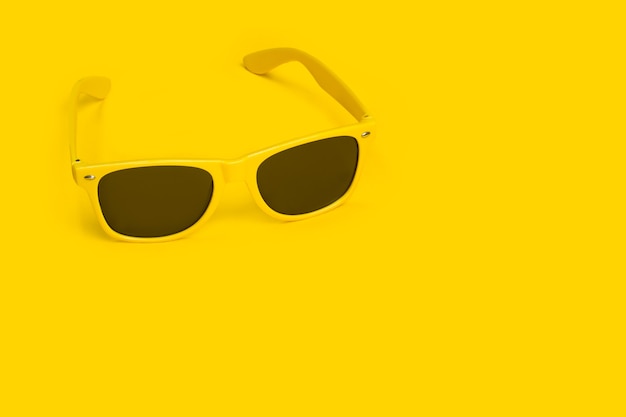 Gele zonnebril op geel met kopie ruimte