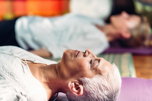 Foto geleide meditatie therapie oudere vrouw die op de vloer ligt te mediteren