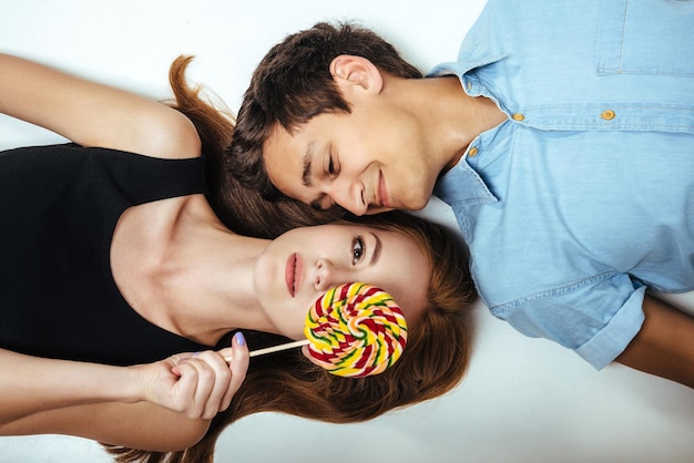 Geliefden liggen op de vloer en bedekken haar gezicht met gekleurde lolly