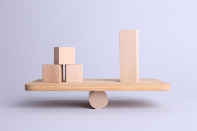 Gelijkheidsconcept Schommelschaal met houten blokken op een lichte achtergrond