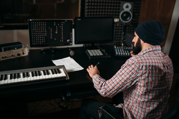 Geluidsproducent werkt met audioapparatuur in studio.