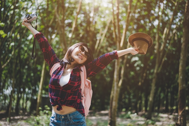 Geluk Aziatische reizigersvrouw in bos met uitgespreide wapens en geniet van verse lucht