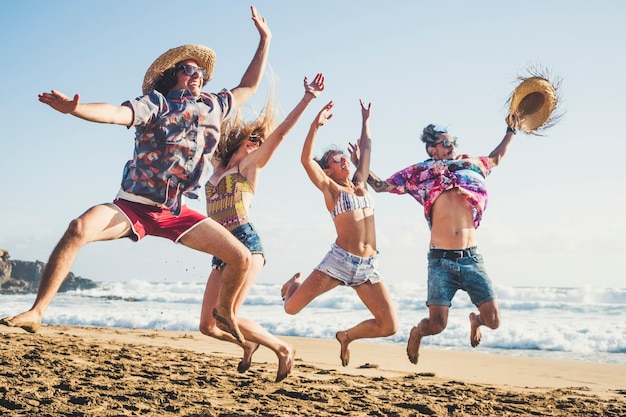 Geluk en jeugdige generatie mensen hebben samen plezier in vriendschap op de ebach voor zomervakantie vakantie springen als een gek en veel lachen met blauwe zee en lucht op de achtergrond