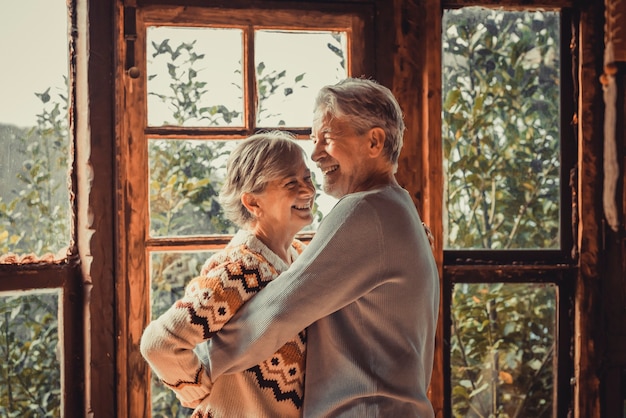 Geluk en saamhorigheid concept levensstijl met senior gepensioneerd kaukasisch echtpaar genieten van liefde en relatie thuis knuffelen en lachen. man en vrouw ouderen leven concept indoor