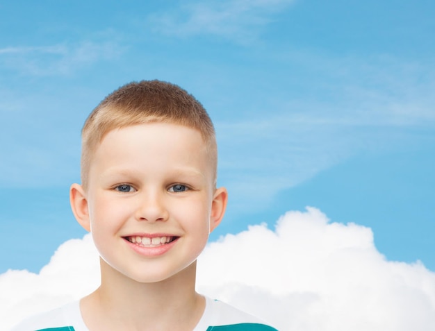 geluk, jeugd, dromen en mensen concept - glimlachend jongetje over blauwe bewolkte hemelachtergrond