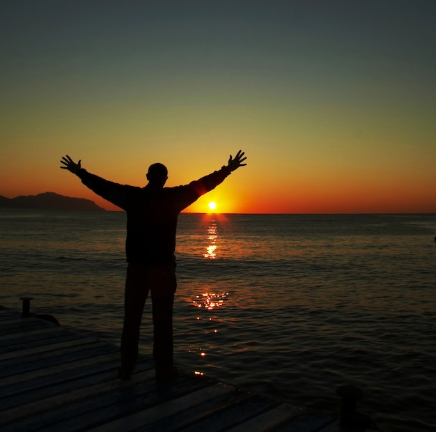 Geluk man silhouet op de zonsondergang