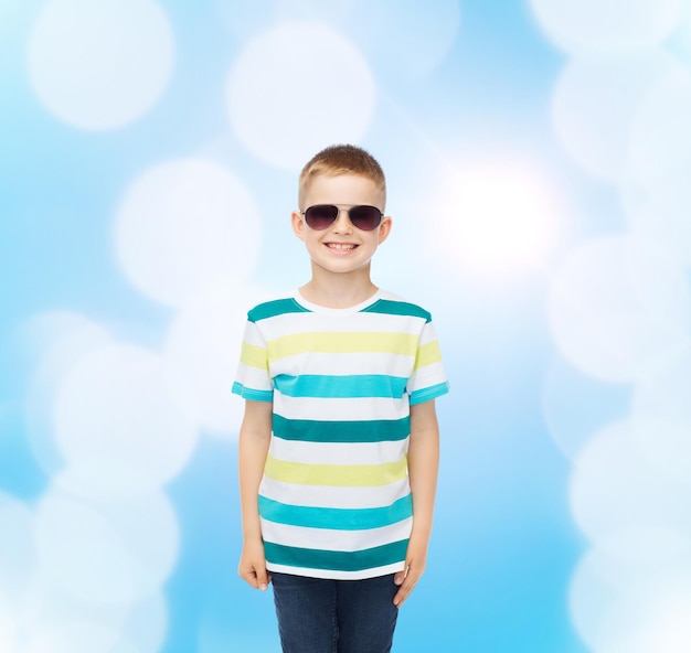 geluk, zomer, jeugd en mensen concept - lachende schattige kleine jongen in zonnebril op blauwe achtergrond