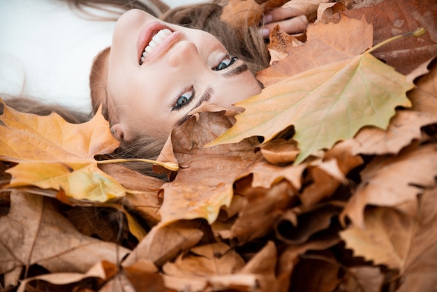 Geluk zorgeloos gelukkig herfst mooi meisje ligt in esdoorn gele bladeren