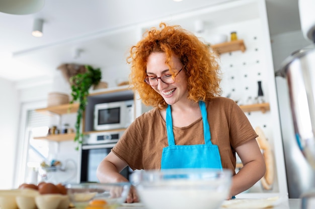 Gelukkig aantrekkelijke jonge volwassen vrouw huisvrouw baker slijtage schort met pin rollend deeg op keukentafel bakken gebak concept koken cake biscuit doen bakkerij zelfgemaakte pizza thuis maken