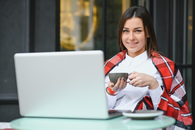 Gelukkig aardige vrouw die op laptop werkt in Street Cafe