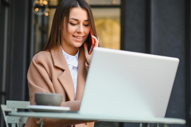 Gelukkig aardige vrouw die op laptop werkt in Street Cafe