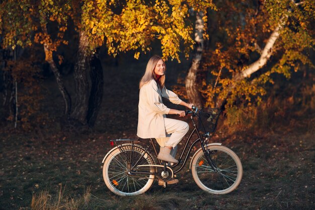 Gelukkig actieve jonge vrouw fietsten in herfst park.