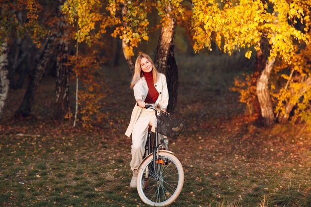 Gelukkig actieve jonge vrouw fietsten in herfst park.