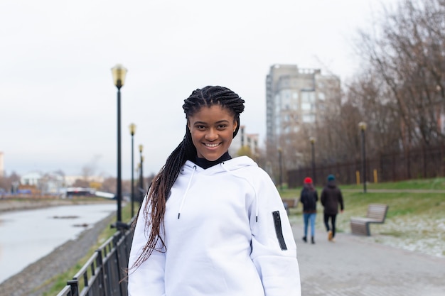 gelukkig African American vrouw in een park in een witte hoodie