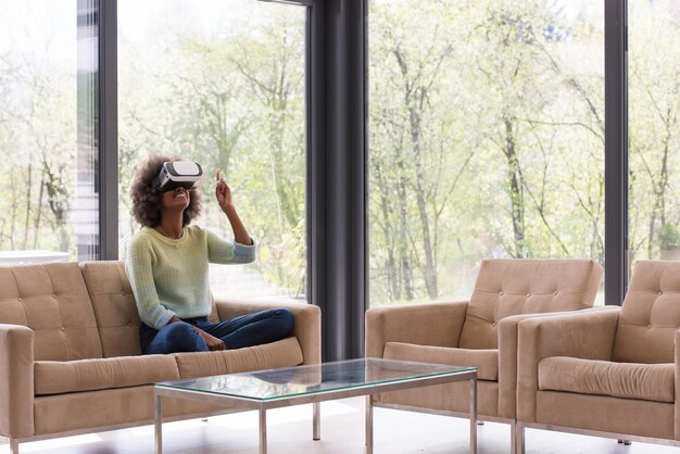 Gelukkig Afrikaans-Amerikaans meisje dat thuis ervaring opdoet met het gebruik van VR-headsetbrillen van virtual reality