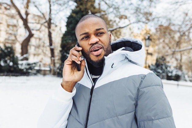 Gelukkig Afrikaanse man praten aan de telefoon glimlachend winter buiten lopen