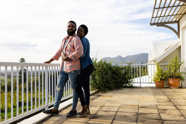 Gelukkig Afro-Amerikaans echtpaar omhelst en verblijft op een zonnig terras.