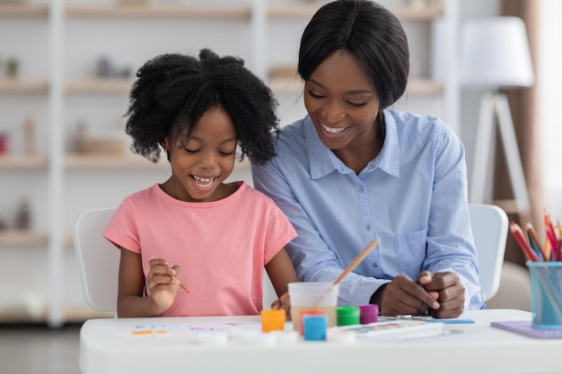 Gelukkig Afro-Amerikaans kind geniet van schilderen op de kleuterschool