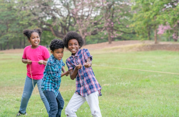 Gelukkig Afro-Amerikaanse kinderen spelen touw touwtrekken in het park Onderwijs buiten concept