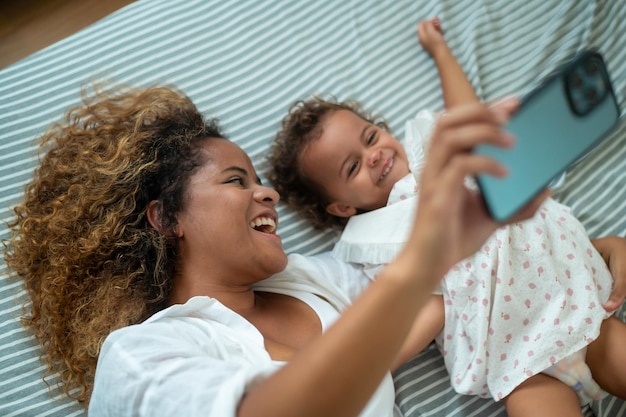 Gelukkig Afro-Amerikaanse moeder speelt met zijn meisje in de slaapkamer thuis