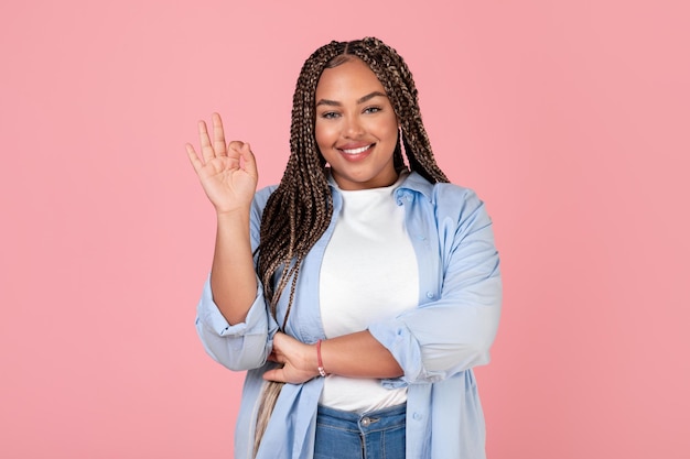 Gelukkig Afro-Amerikaanse overgewicht vrouw OK gebaren over roze achtergrond