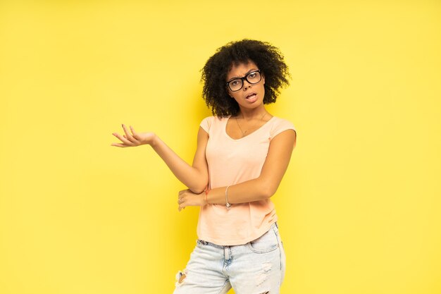 Gelukkig Afro-Amerikaanse vrouw op zoek verrast op gele achtergrond.