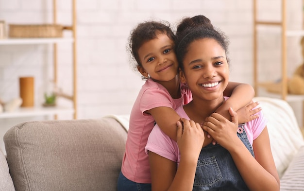 Gelukkig Afro-Amerikaanse zussen knuffelen thuis