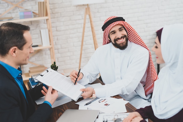 Gelukkig Arabische man tekent overeenkomst glimlach aan vrouw.